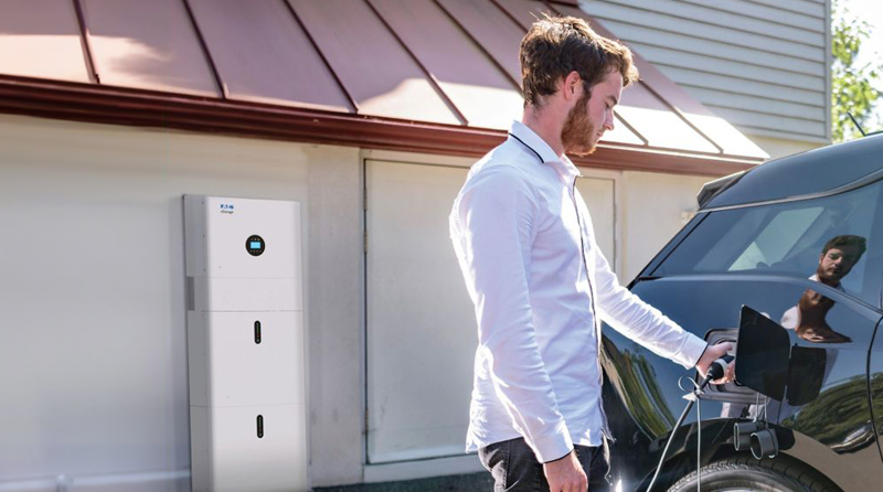Ein Mann im weißen Hemd tankt Energie in sein schwarzes E-Auto