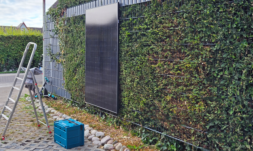 Ein montiertes PV-Panel am Zaun, mit einer Leiter und einem türkisen Werkzeugkoffer davor